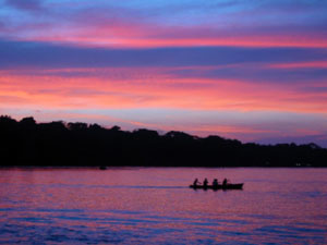 Amérique Centrale, Costa Rica, Tortuguero, pirogue passant sur la rivière et coucher de soleil