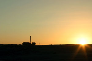 Paysage desertique chilien avec ancienne usine abandonnee et soleil couchant